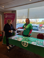 Picture of a person handing another person a leaflet at an event