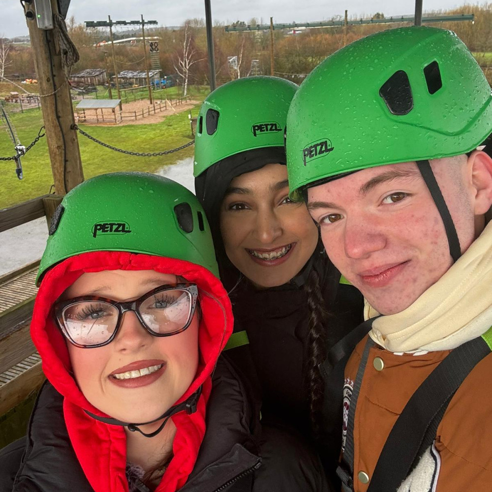 Three young people wearing helmets at an outdoor activity park