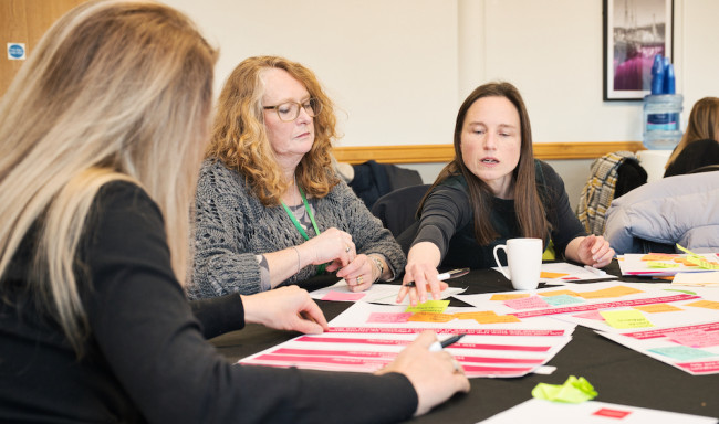 Image showing three people sat around a table making notes on a piece of paper