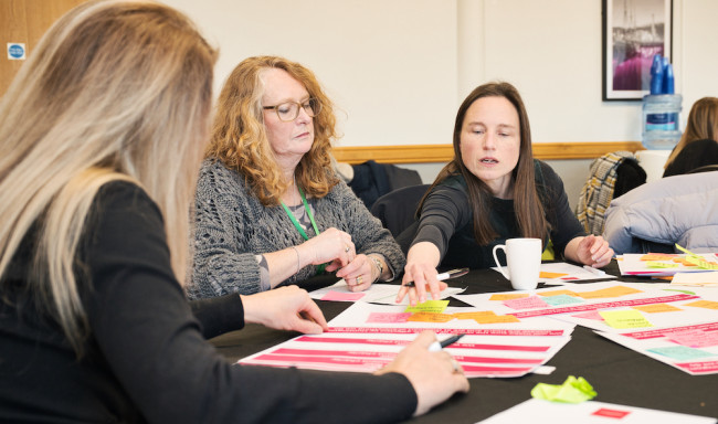 Image showing three people sat around a table making notes on a piece of paper