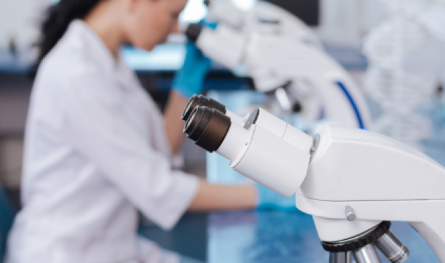 A picture in a laboratory with a microscope and a woman in the background