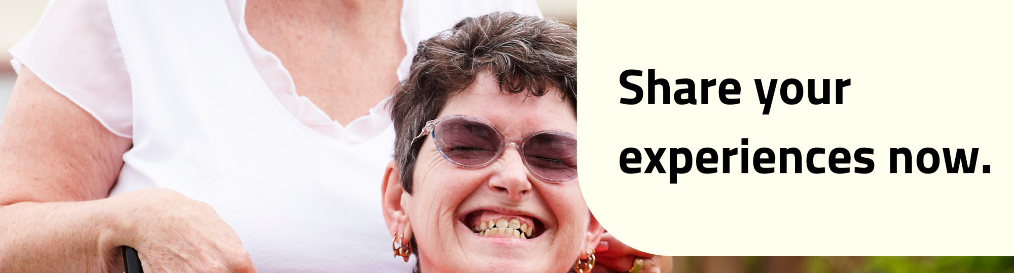 Image of two ladies.One in a wheelchair the other is behind. They are both smiling.