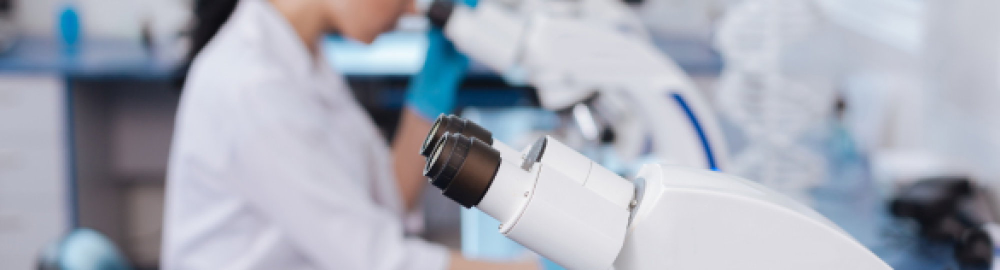A picture in a laboratory with a microscope and a woman in the background