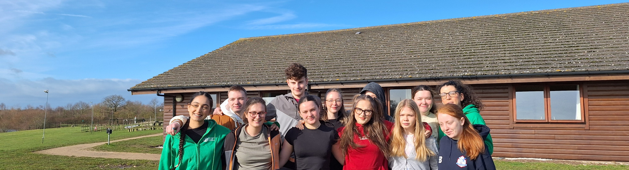 12 young people standing in a group photo with their arms round each other representing unity